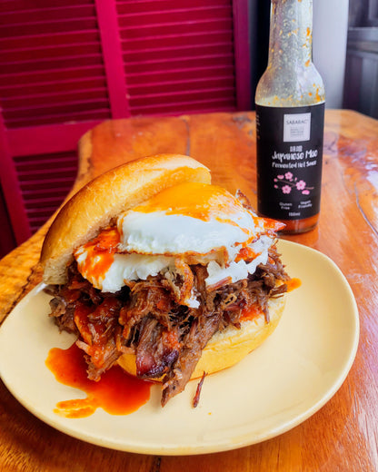 Brisket Burger topped with a fried egg on a brioche bun lashed with Sabarac's Fermented Japanese Miso Hot Sauce